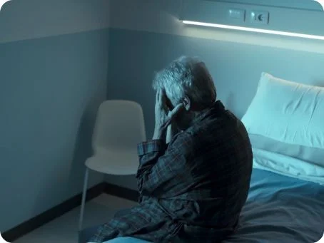 Einsatz von medizinischem Cannabis bei Alzheimer und Demenz Ältere Person sitzt verzweifelt und alleine im dunklen Krankenhauszimmer