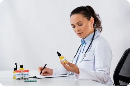 Ärztin schaut sich CBD-Extrakt an und füllt ein Rezept aus