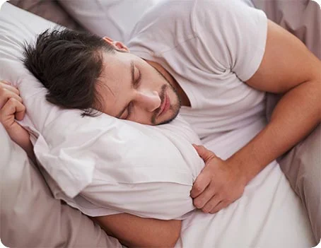 Schlafender Mann liegt entspannt im Bett