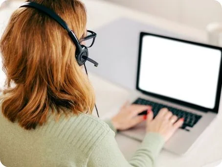 Frau mit Headset arbeitet an einem Laptop
