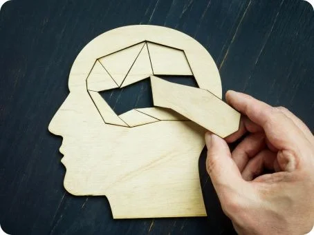 Erfahrungsbericht - Demenzerkrankung Holzfigur eines Kopfes mit herausnehmbarem Puzzleteil im Gehirnbereich