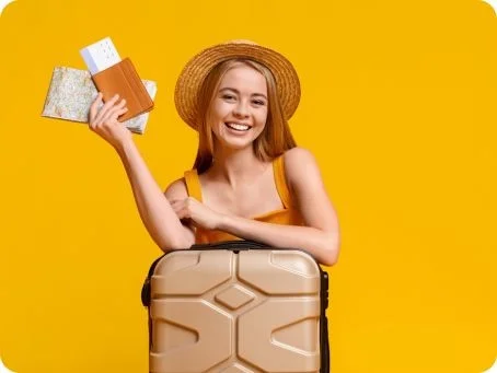 Reisen mit cannabisbasierten Arzneimitteln Lachende Frau mit Hut, Koffer und Reisedokumenten vor gelbem Hintergrund